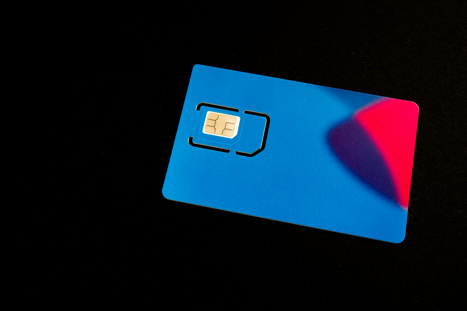Blue SIM card with gold chip on a dark surface