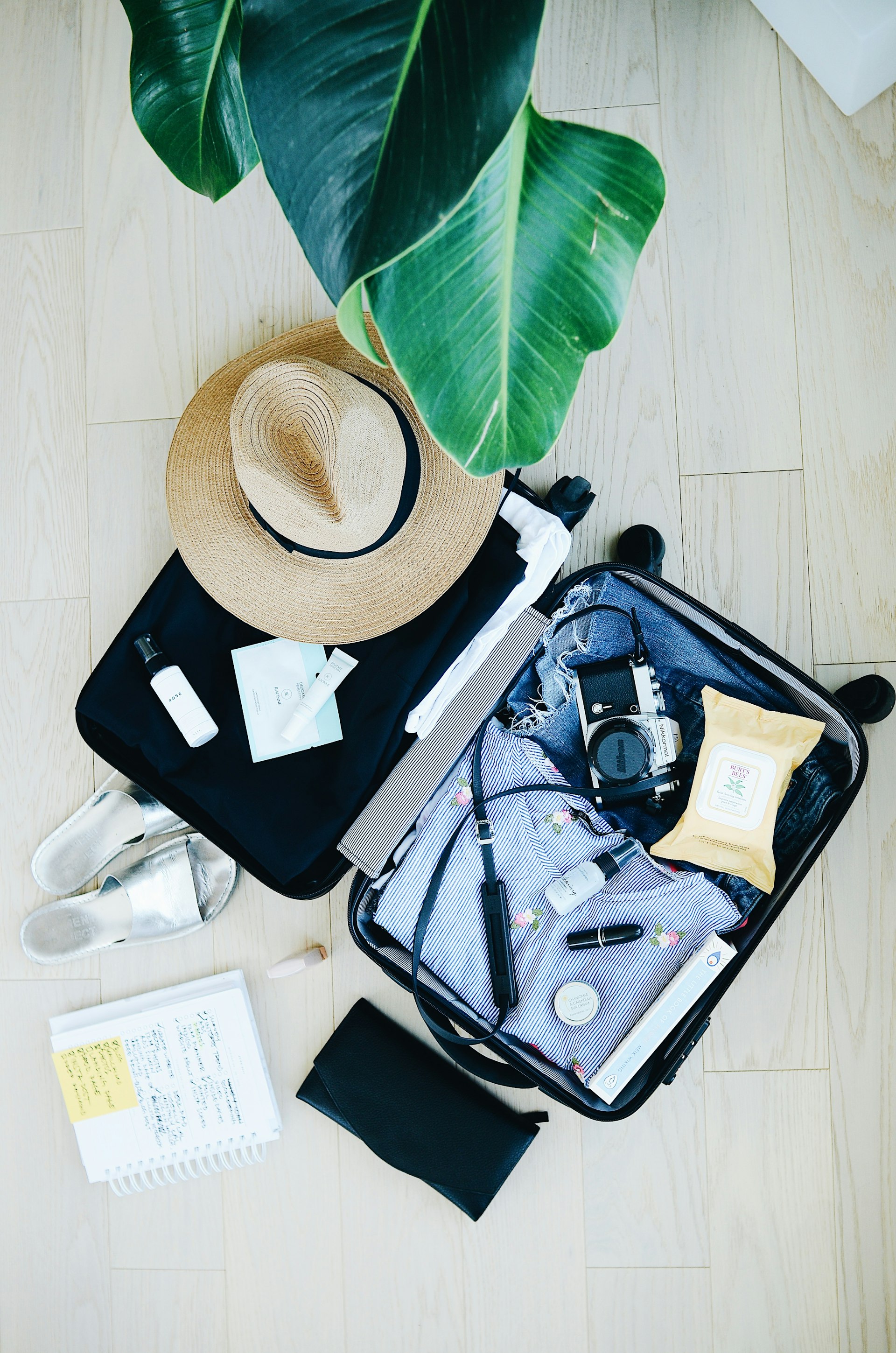 Open suitcase with travel clothes and a hat