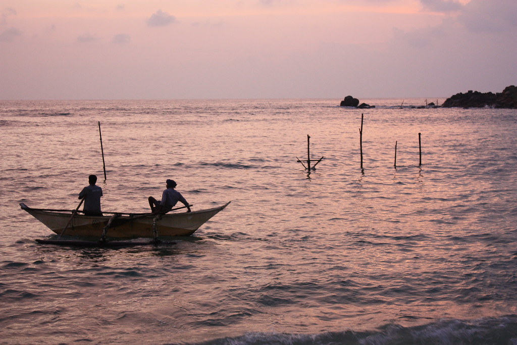 Fishermen in an outrigger canoe at dawn off Mirissa