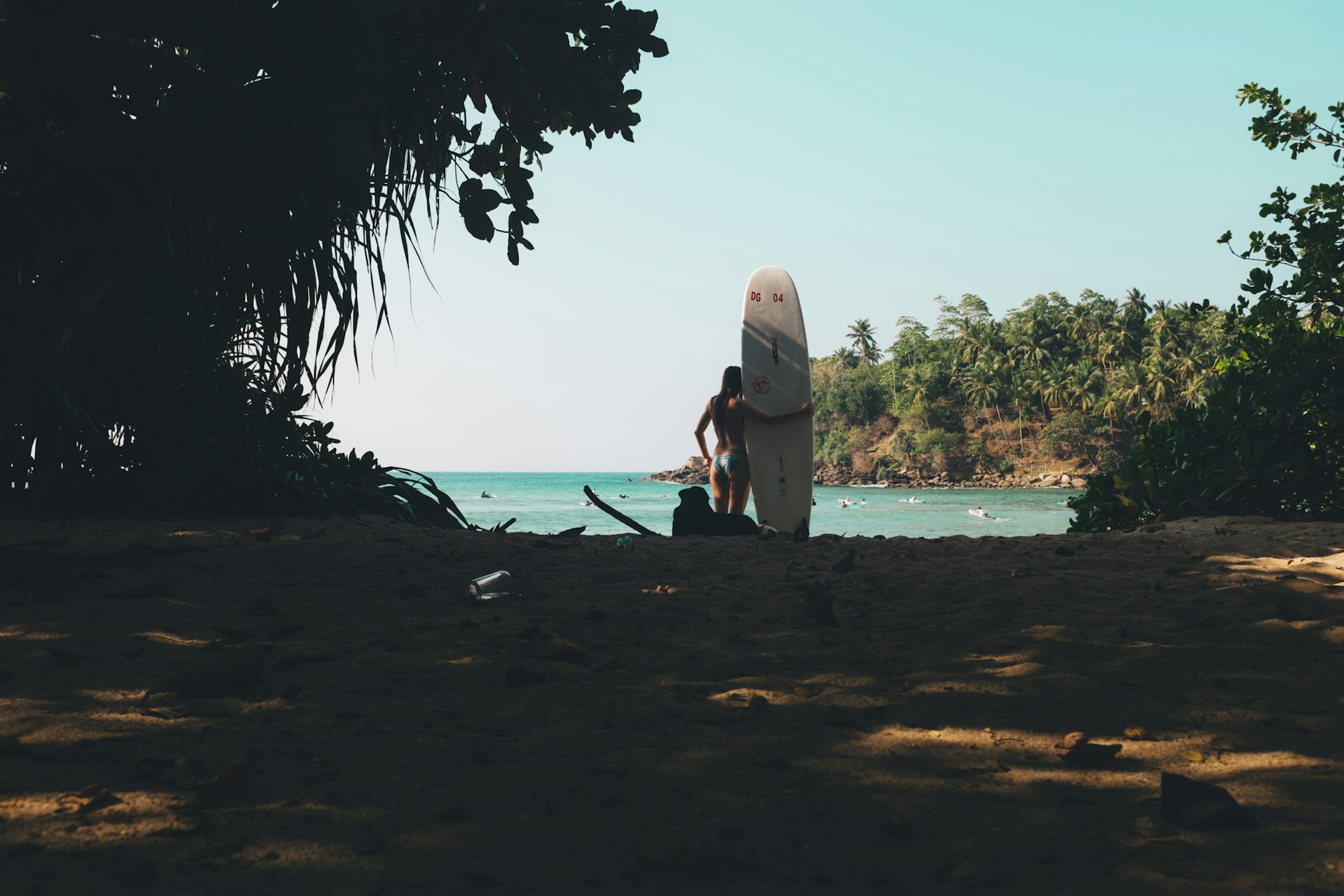 Person holding a white surfboard on the shore