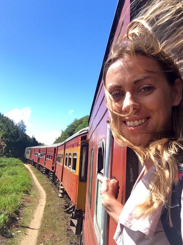 A traveller leans from the open door of a hill-country train near Ella
