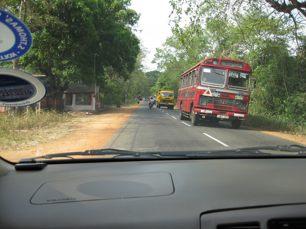 A red SLTB bus on a country road, seen through a windscreen